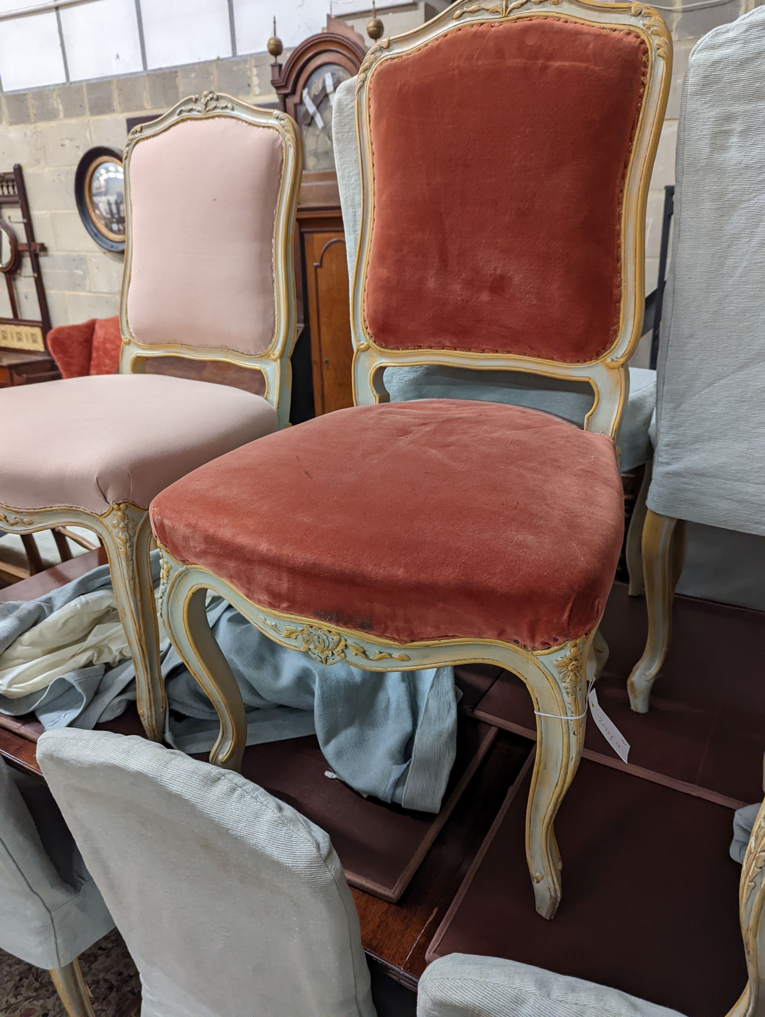 A set of fourteen French Louis XV style painted upholstered dining chairs with loose covers